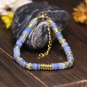 Dettaglio del bracciale con perle in pietra blu e distanziali dorati regolabili