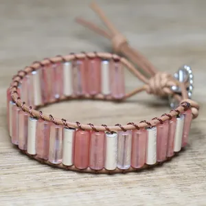 Macro detail showing the texture of pink natural stone tubes and silver beads on leather