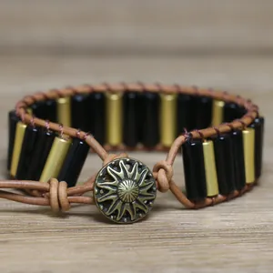 Close-up of a handmade leather woven bracelet featuring natural stone tubes and a sun button