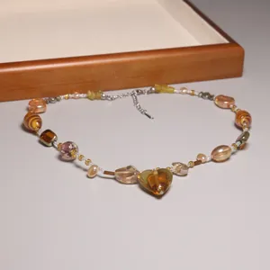 Vue détaillée d'un collier vintage en perles de verre avec un pendentif cœur doré.