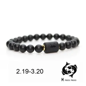 Primer plano de pulsera de cuentas de piedra negra mate con símbolo del zodiaco de Piscis
