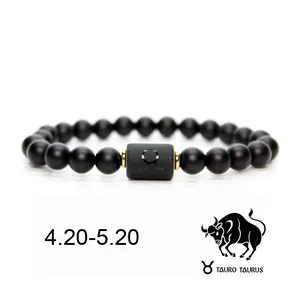 Detalle de la pulsera del zodiaco Tauro en piedras negras mate con icono y fechas