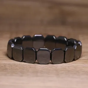 Detail shot of a minimalist black hematite stone stretch bracelet on wooden surface