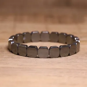 Detailed macro view of a metallic grey hematite elastic bracelet with square stone beads