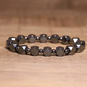 Detailed macro shot of hematite bracelet with geometric beads on wooden background