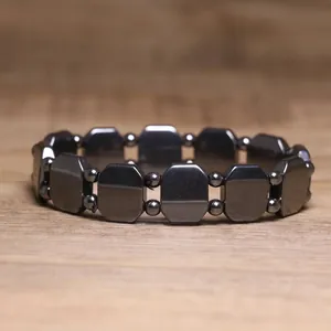 Close-up of a hematite bracelet with octagonal metallic beads on a wood surface
