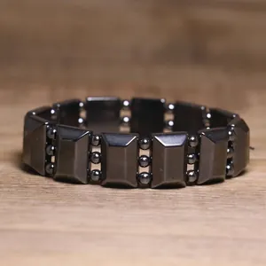 Detail view of a black hematite elastic bead bracelet on a wooden surface