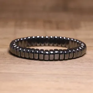 Close-up macro view of a metallic hematite beaded elastic bracelet on wood surface