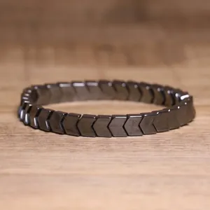 Close-up of a dark grey hematite chevron bead elastic bracelet placed on wood surface
