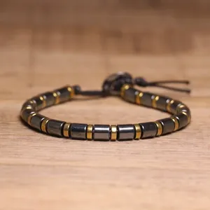 Detailed macro view of a hematite stone bracelet with gold metal spacers on wood