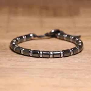 Detailed macro view of hematite cylindrical beads and silver-toned spacers on a bracelet.