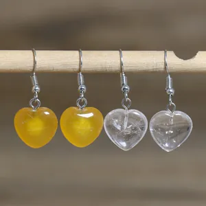 Detailed macro view of heart-shaped natural stone earrings hanging on a rustic wooden rod