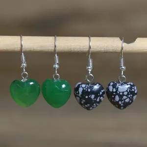 Close-up of heart-shaped natural stone earrings hanging on a rustic wooden display