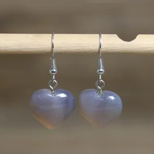 Detailed macro view of heart-shaped natural stone pendant earrings on a minimalist wooden rod