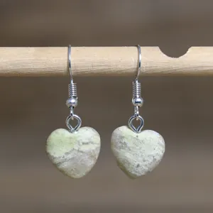 Macro view of natural stone heart earrings showcasing unique textures and hooks.