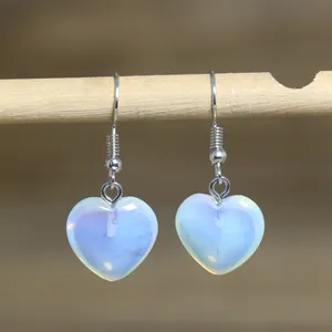 Close-up detail of translucent heart-shaped stone dangles on minimalist silver hooks