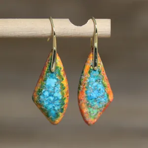 Primer plano de pendientes colgantes de piedra imperial retro con ganchos dorados en madera.