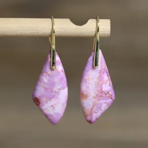 Primer plano de pendientes de piedra emperador púrpura con ganchos dorados en madera