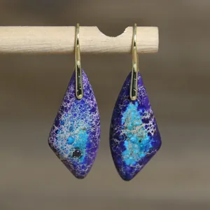 Primer plano de pendientes colgantes vintage de piedra natural con patrones morados y azules.