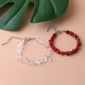 Close-up detail of natural irregular clear crystal and red stone chip charm bracelets