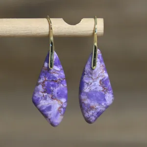 Primer plano de pendientes colgantes de piedra imperial morada con forma de abanico.