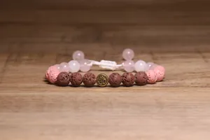 Detailoverzicht van handgemaakte lavasteen armband met roze kralen en gouden Om-bedel