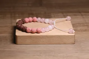Detailopname van een handgemaakte kralenarmband met roze en bruine lavastenen erop