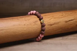 Detail van lavasteen armband met roze bruine kralen en Om-bedel