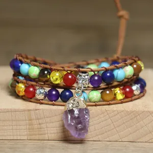 Detailed view of bohemian wrap bracelet with raw amethyst pendant and colorful beads.