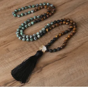 Detailed view of natural tiger eye and lava stone beaded necklace with black silk tassel.