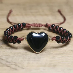 Detail eines schwarzen Herzsteins an einem braunen geflochtenen, verstellbaren Perlenarmband.