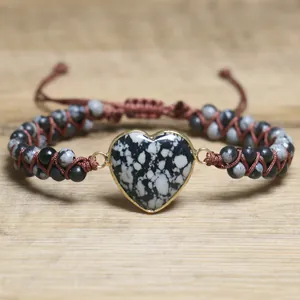 Nahaufnahme eines handgeflochtenen Armbands mit herzförmigem Schneeflocken-Obsidian-Stein.