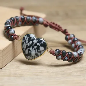 Makroaufnahme des herzförmigen Naturstein-Armbands mit handgewebter brauner Kordel