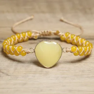 Nahaufnahme eines gelben Herz-Naturstein-Armbands auf einem rustikalen Holzuntergrund