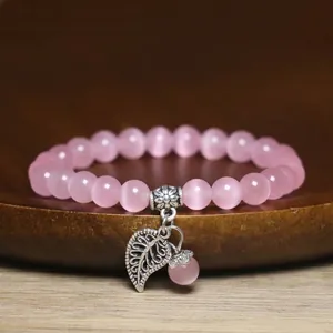 Detailed view of pink cat's eye bead bracelet with silver leaf charm pendant