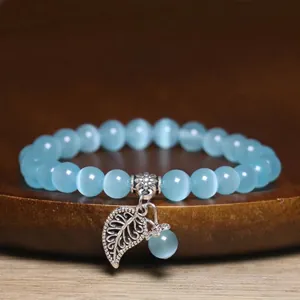 Close-up of blue cat's eye stone bead bracelet with detailed silver leaf charm