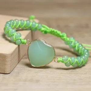 Detailaufnahme eines handgewebten grünen Natursteinarmbands mit einem herzförmigen Stein.