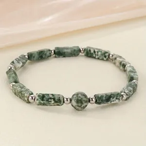 Close-up of a green marbled stone energy bracelet with silver beads on a silk background