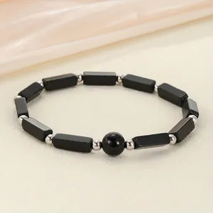 Detailed view of black stone bar and round bead energy bracelet with silver spacers
