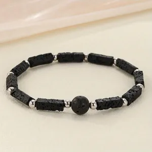 Detail view of a handcrafted black lava stone bracelet featuring decorative silver beads