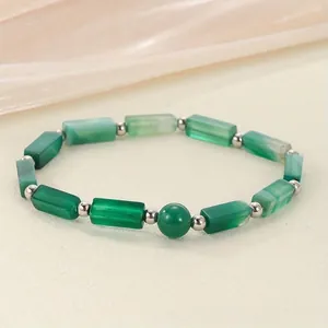 Close-up of green stone bead bracelet with silver spacers on soft textured background