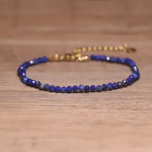 Macro detail of handmade faceted blue lapis lazuli stone beads with a gold extender chain