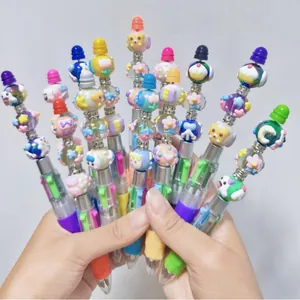 Handgehaltene Anzeige bunter DIY-Perlenstifte mit 4 Farben und süßen Cartoon-Figuren-Anhängern.