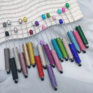 Detail showing various colors of DIY rhinestone stylus pens on a textured white display.