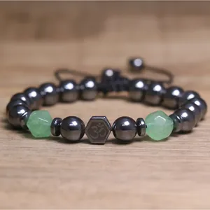 Gedetailleerd overzicht van gefacetteerde hematiet en groene stenen armband met Om-bedel