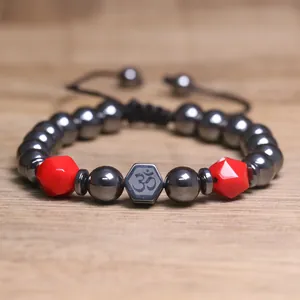Detail van hematiet kralenarmband met rode kralen en Om-symbool
