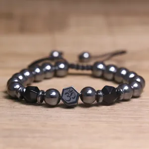 Detailopname van hematiet kralenarmband met Om-symbool en gefacetteerde accenten