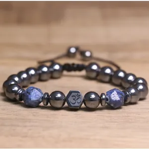 Detailopname van hematiet kralenarmband met blauwe lapis lazuli en Om-symbool bedel.