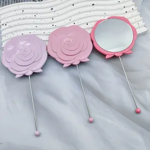 Detail view of rose-shaped handheld mirrors in purple and pink tones with metal stems