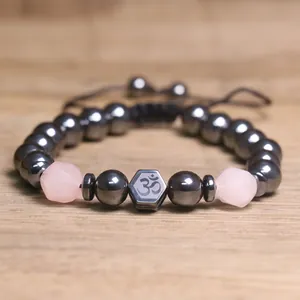 Gedetailleerd macro-overzicht van hematiet kralen en rozenkwarts met Om-symbool op armband